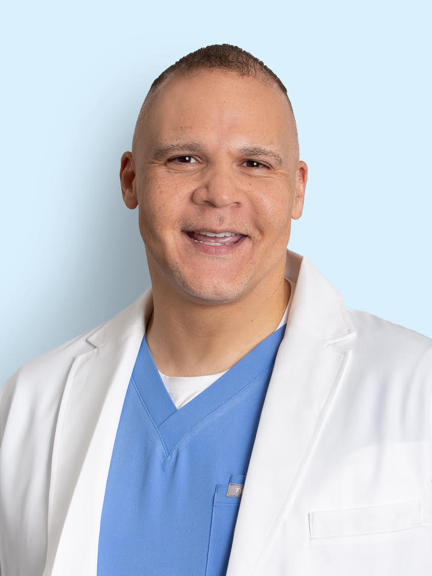 a white man in blue scrubs and a white coat