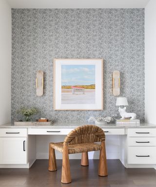 Neutral home office with gray wallpaper and framed beach print above desk
