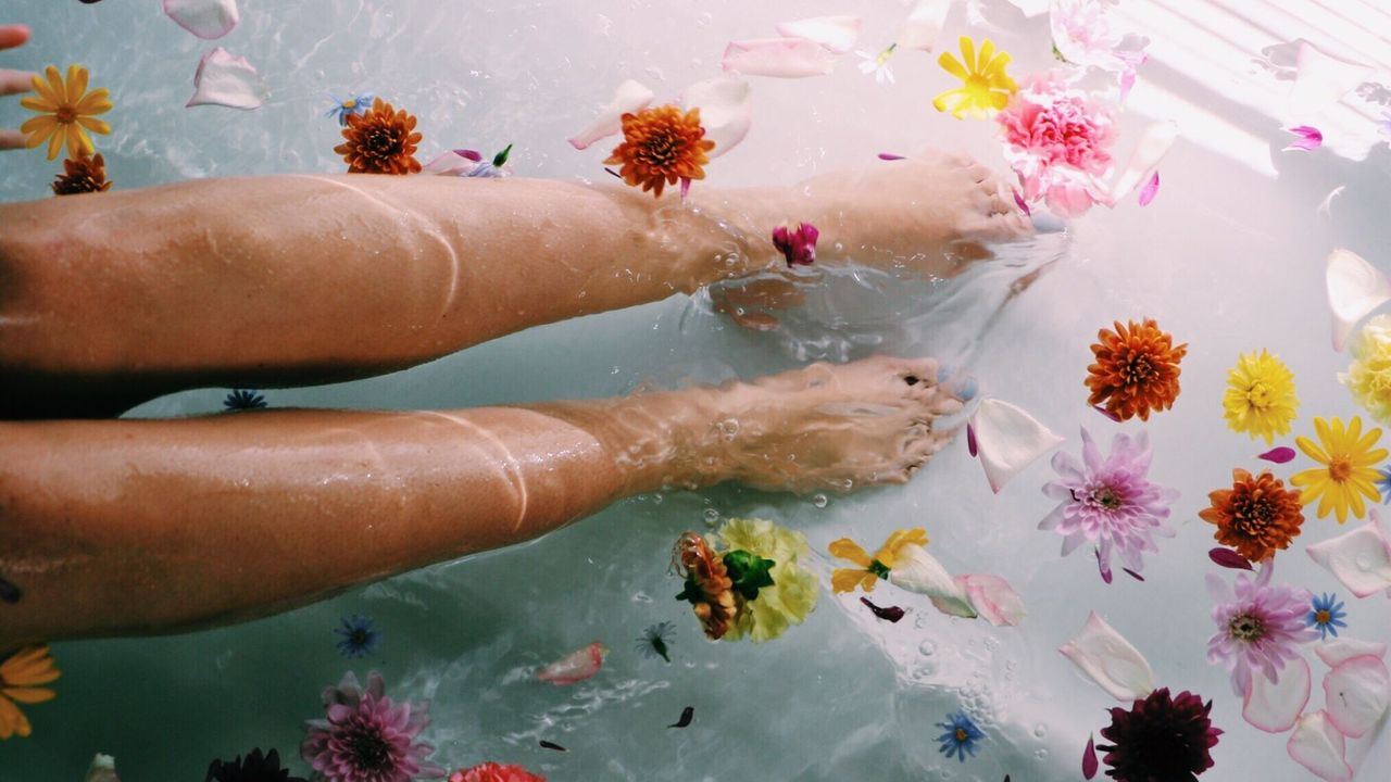 Woman in bath with flowers and essential oils: Essential oils for stress