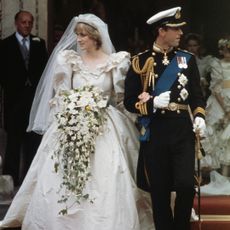 Princess Diana on her wedding day wearing a long white gown and standing with King Charles, who is wearing military uniform