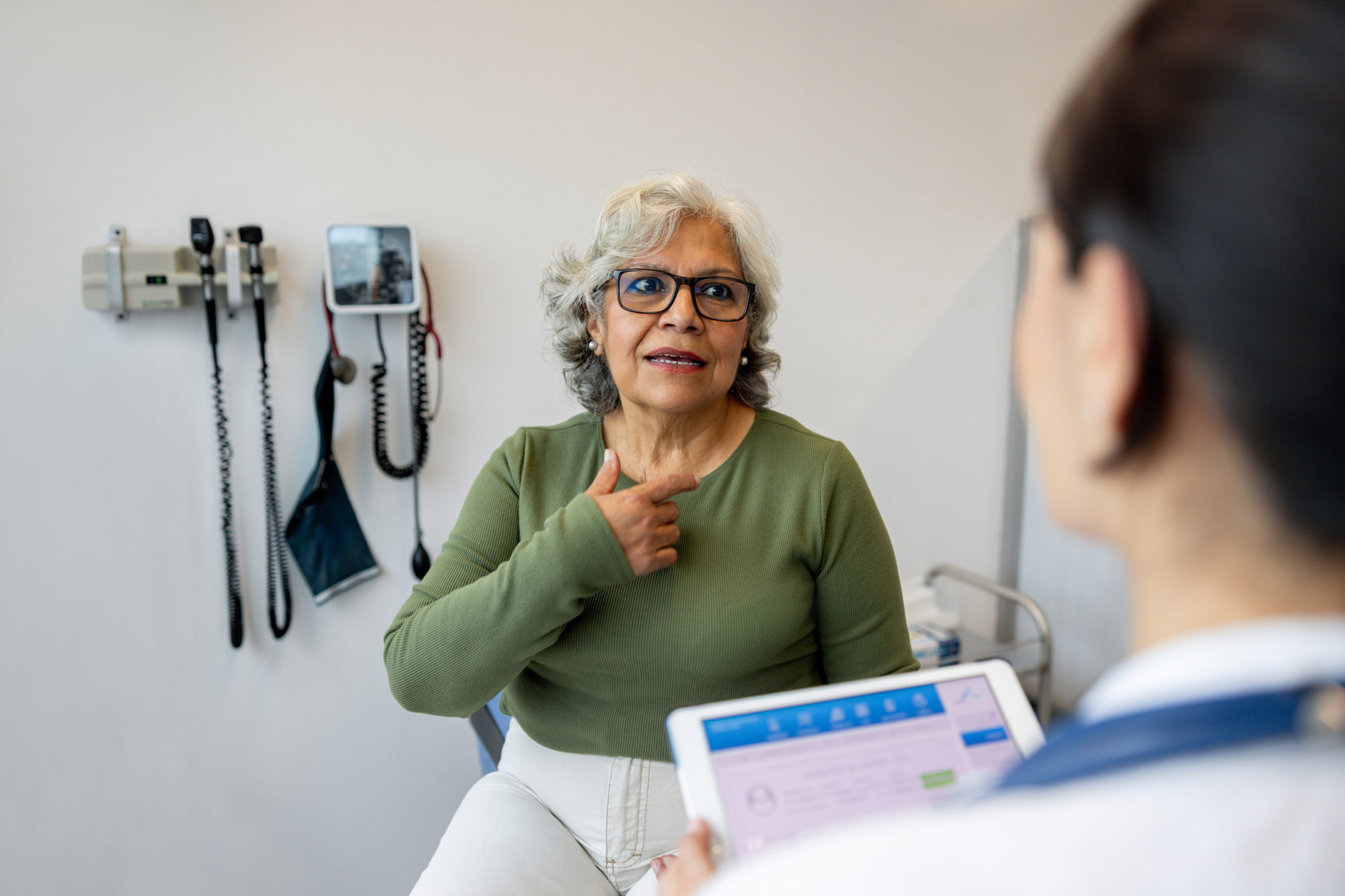 Latin American senior woman explaining her symptoms to a doctor in the consultation room