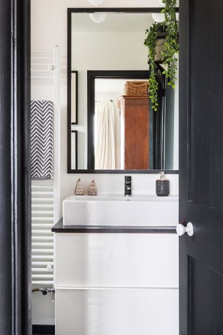 A peep into the en suite bathroom, monochrome decoration, sink and large bathroom mirror