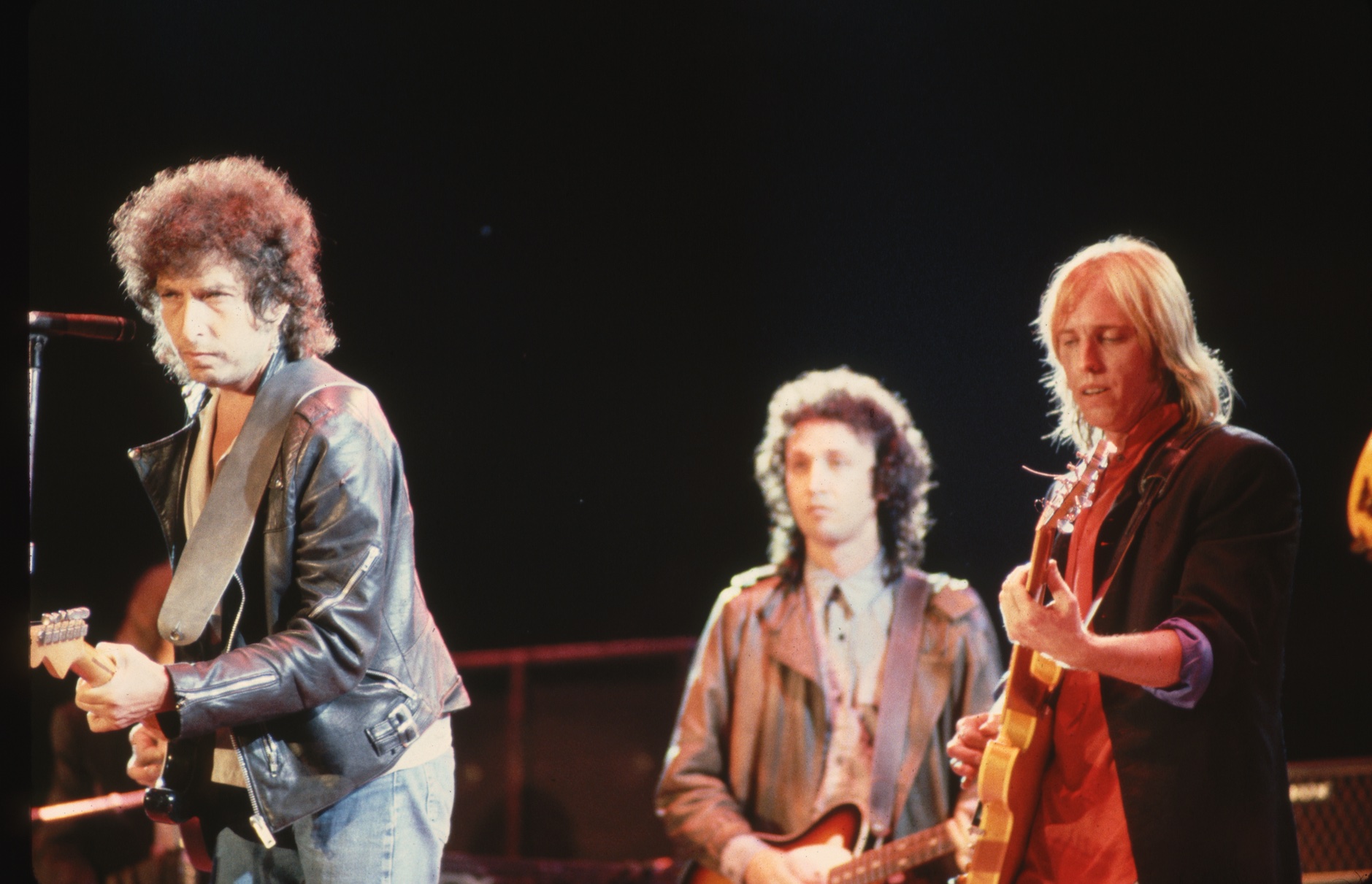 Bob Dylan, onstage with Tom Petty (right) and Mike Campbell (center, background)