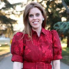Princess Beatrice smiling outside in a red dress 