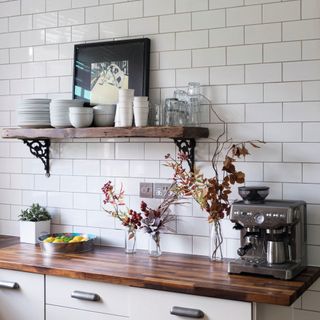 Detail of white cupboards with wooden top in kitchen, white wall tiles.