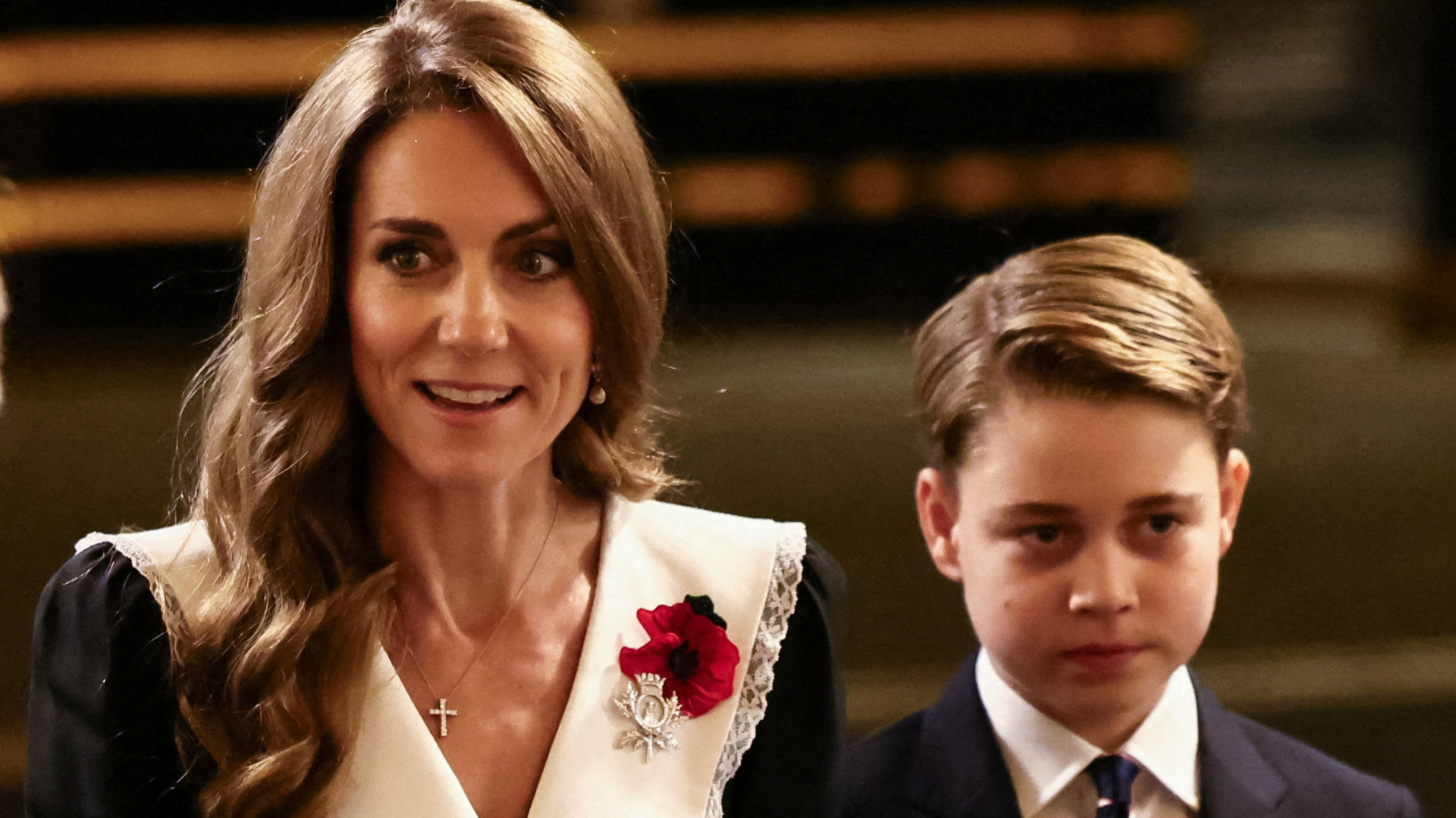 Princess Kate wears a giant white pilgrim collar with a black dress and a red poppy, and her son Prince George wears a black suit