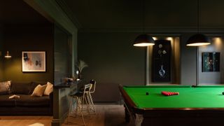 gaming room idea decorated in dark green with pool table and cosy nook