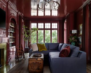 living room with color-drenched walls in dark red wine color with a gloss finish, gray-blue sofa and velvet cushions