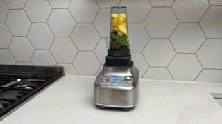 Breville the Super Q filled with pineapple and spinach on a kitchen countertop