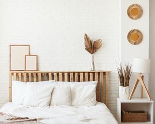 white boho bedroom with white bed wooden headboard and accents