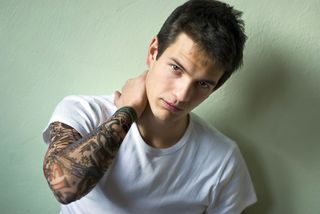 A young man with tattoos covering his arm.
