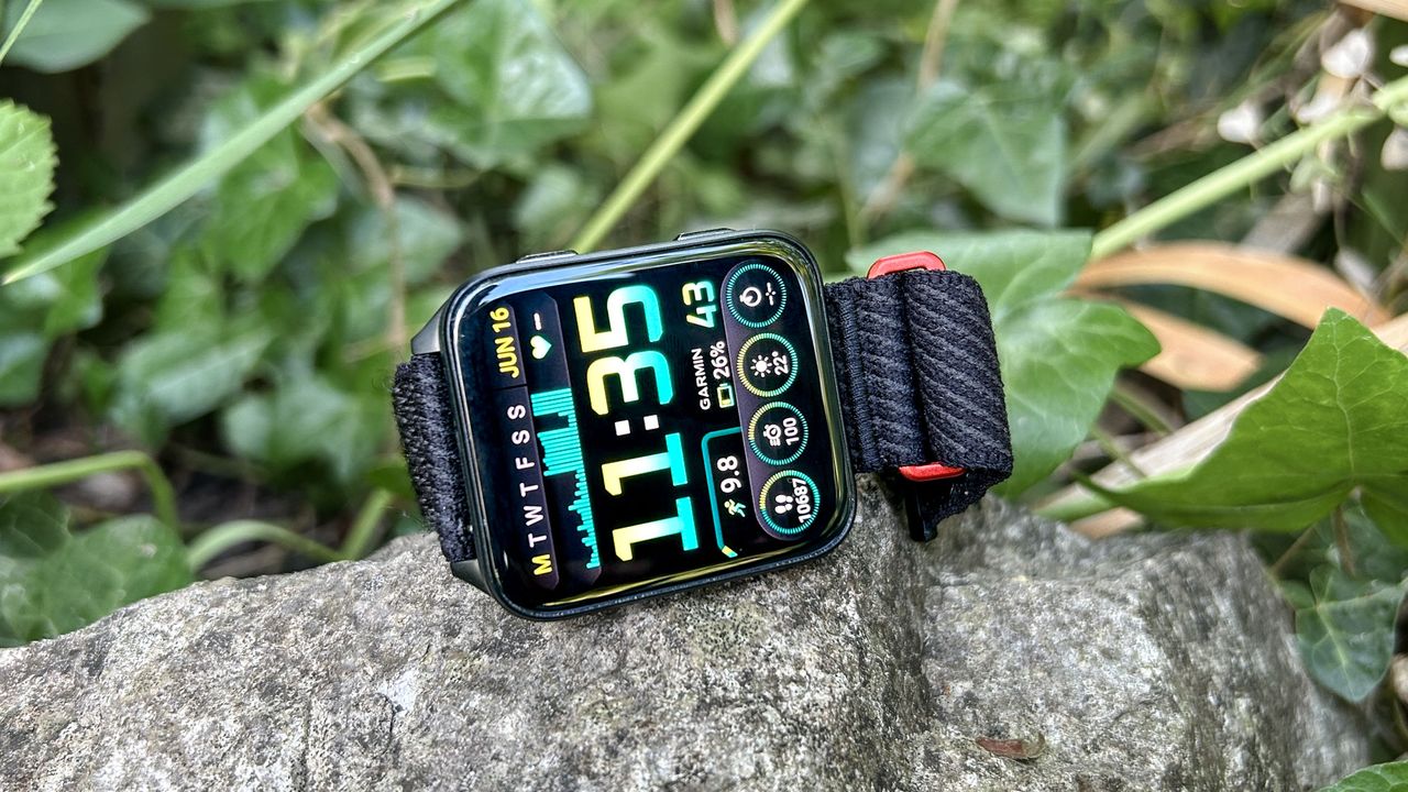 Garmin Venu X1 on a rock showing the watch face