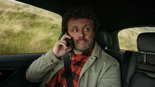 Michael Sheen on the phone in a car in Staged