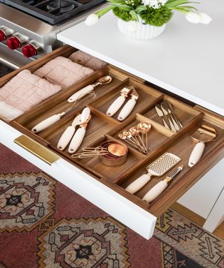 Kitchen island drawer with cutlery divider and a selection of utensils and table linens
