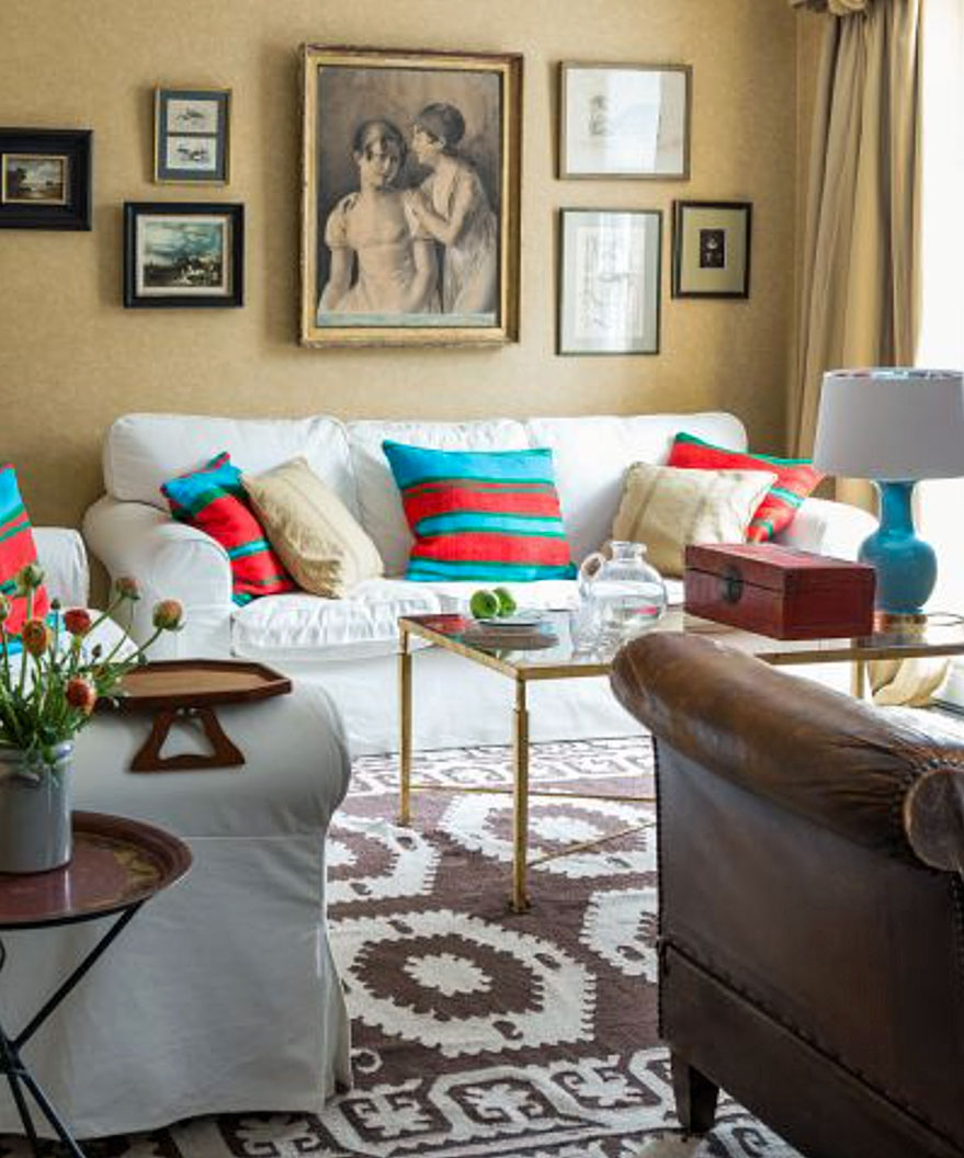 A neutral living room with gallery wall and blue and red accents through the choice of cushions.