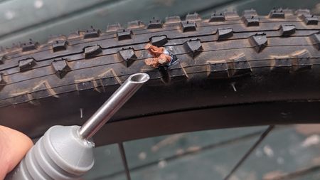 A tubeless plug sticking out of a gravel tyre having been fitted by the Blackburn Plugger puncture repair tool