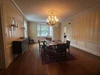 A dining room with wooden flooring, wooden furniture, and a chandelier above