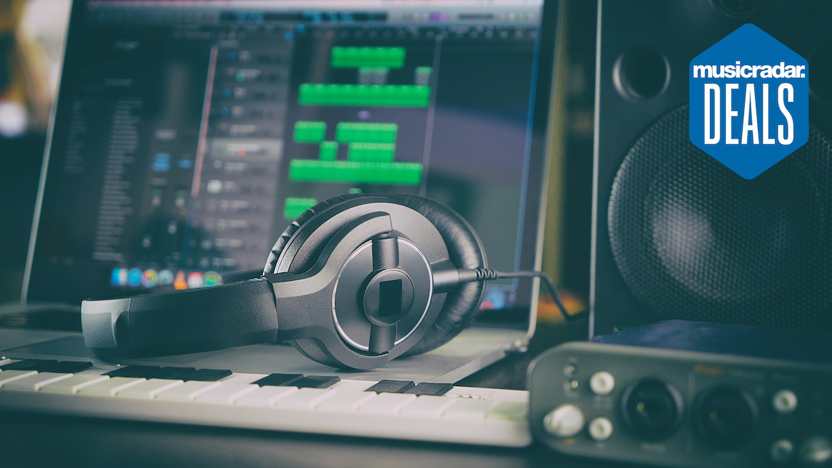Pair of headphones resting on a laptop next to an audio interface and speaker
