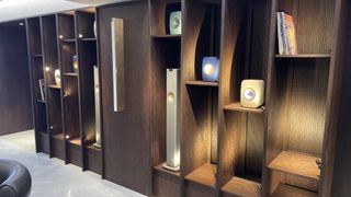 Different KEF speakers arranged in a display cabinet on a wall