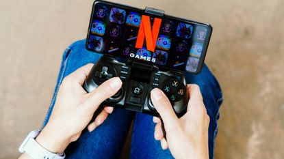 a person playing on a joystick and the Netflix Games logo displayed on a smartphone screen