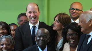 Kate Middleton smiling at Prince William surrounded by a group of people