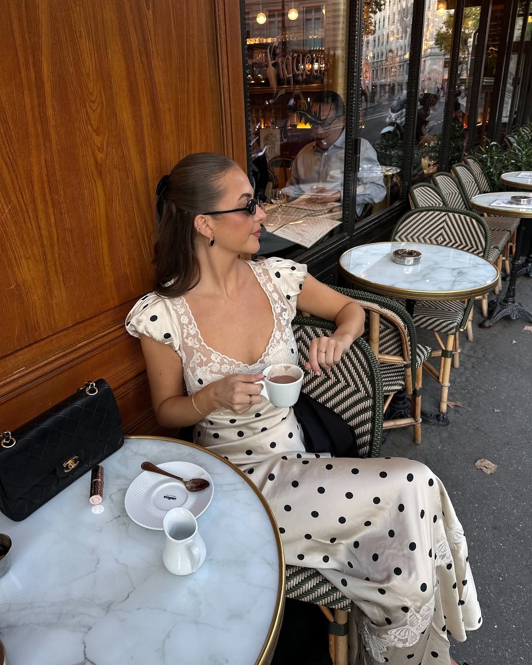 Influencer Nicole Kenway in a black on white silk polka dot dress with a lace trim and puffed sleeves.