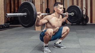 Man in the gym performing a barbell back squat