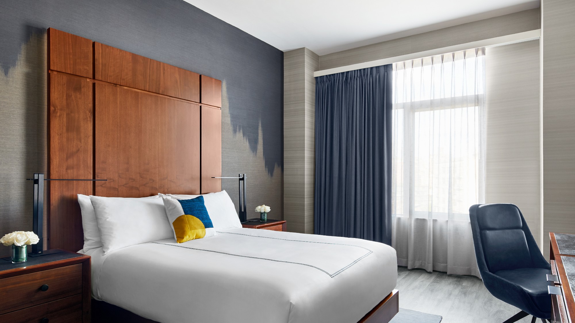 a room at The Gansevoort, with ombre blue-grey wallpaper and a walnut headboard