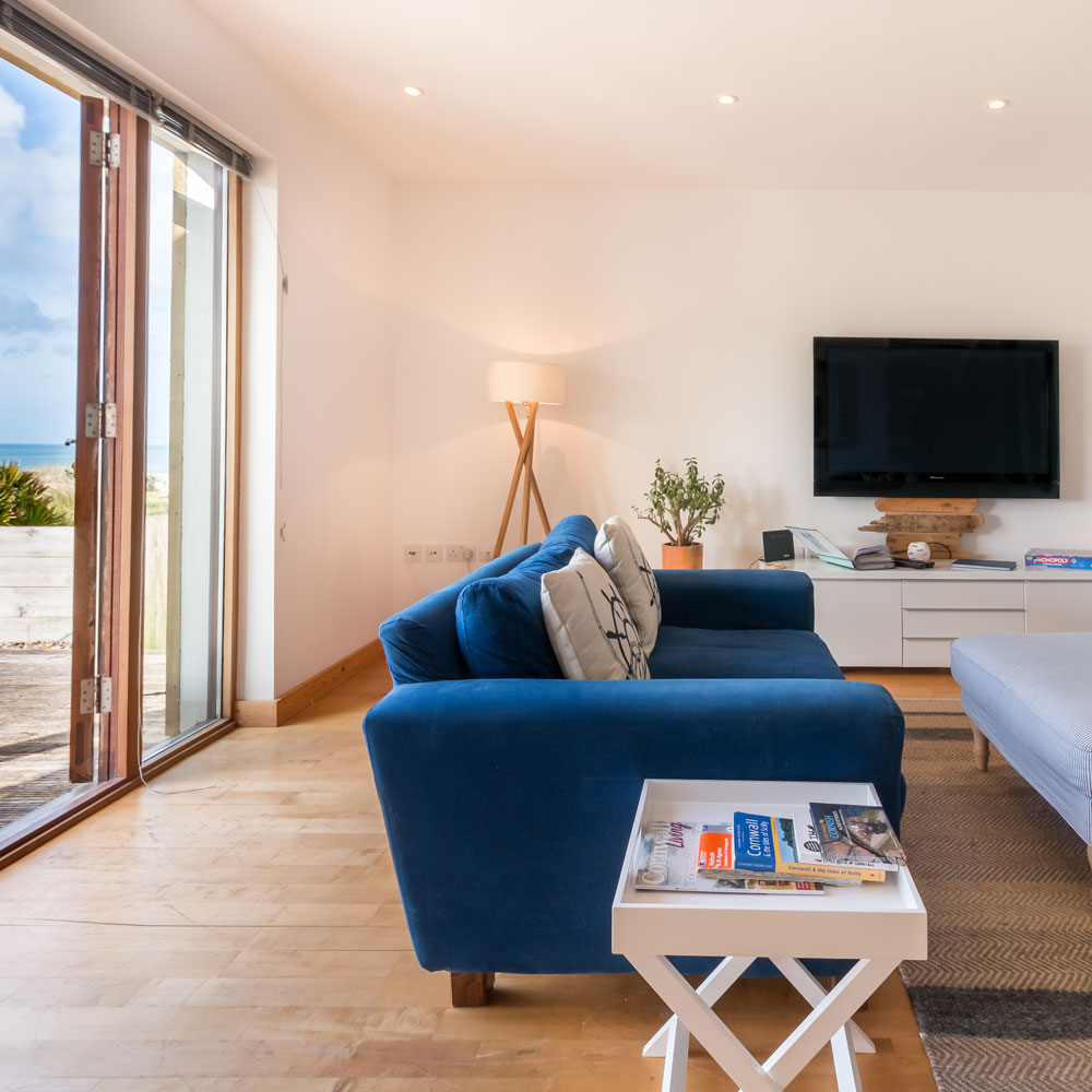 room with wooden flooring blue sofa set and white wall