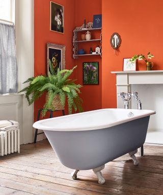 Bathroom with orange walls and gray painted roll-top bath