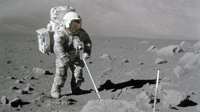 An astronaut in a white spacesuit stands on the surface of the moon with a metal detector.