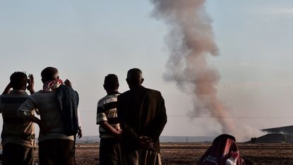 Men watching smoke after an air strike in Kobane 
