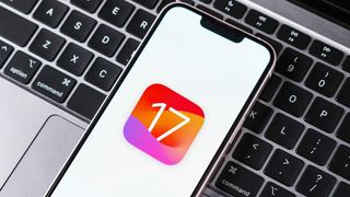 iOS 17 logo on iPhone sitting on MacBook keyboard 