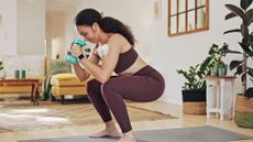 Woman doing a squat with light weights in a stylish living room
