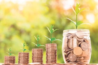 Plants growing from stacks of coins, both increasing in size from left to right. The far right stack has been replaced by a glass jar full of coins