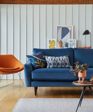 blue sofa and orange chair against white panelled wall with coffee table