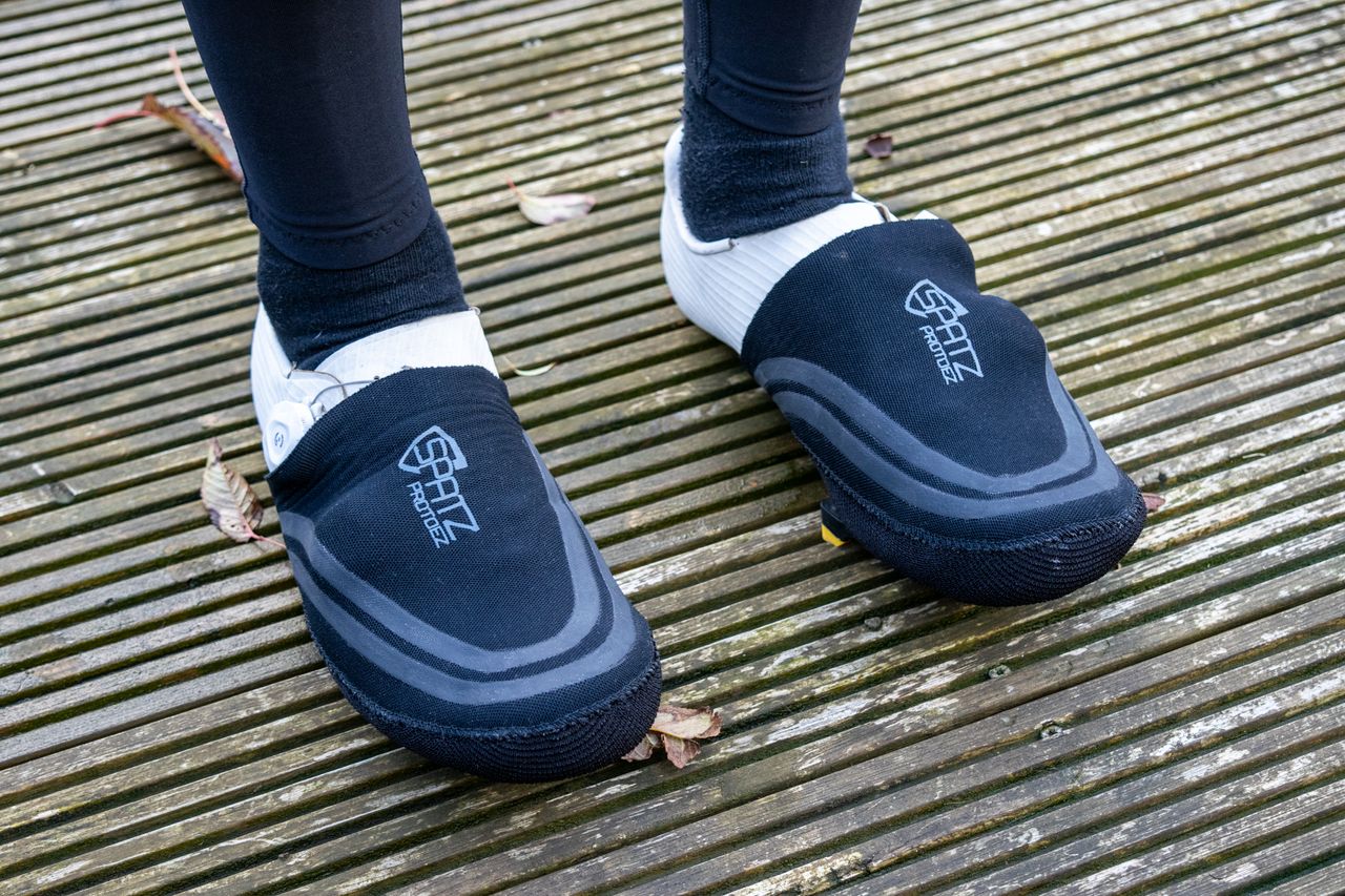A cyclist wearing Spatz Pro Toez toe covers on wooden decking