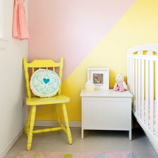 Nursery with cot, yellow chair and yellow pink painted walls