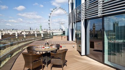 An image of the view from the Radisson Hotel at Westminster Bridge. At the foreground is decking with a table and four chairs. The London Eye can be seen in the distance.
