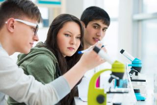 Three students work with microscopes. 
