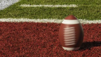 A football spins in the red zone on a football field.