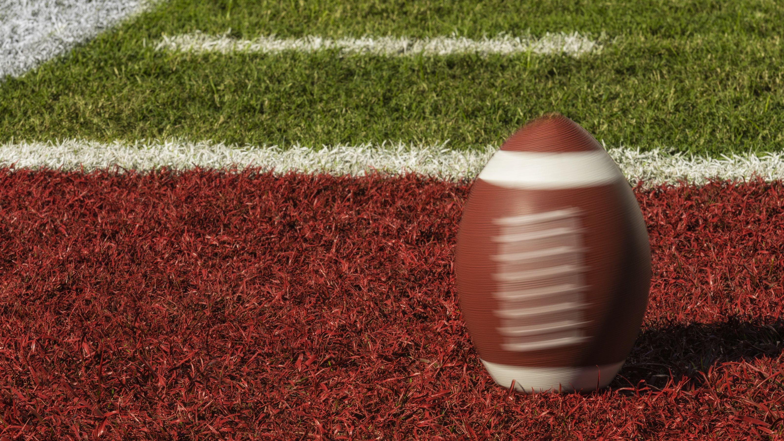 A football spins in the red zone on a football field.