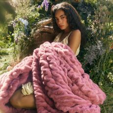 Young woman in plants and flowers wearing pink Lola Blanket
