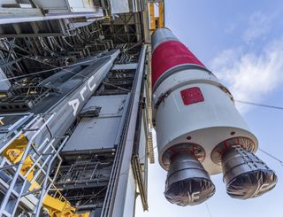 a rocket hangs suspended outside an assembly hanger.