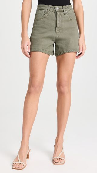 a model wears green shorts with heels