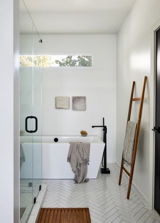 Bathroom with white walls and floor and wooden mat and ladder