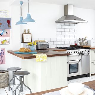 white kitchen with wooden worktop and hanging lights