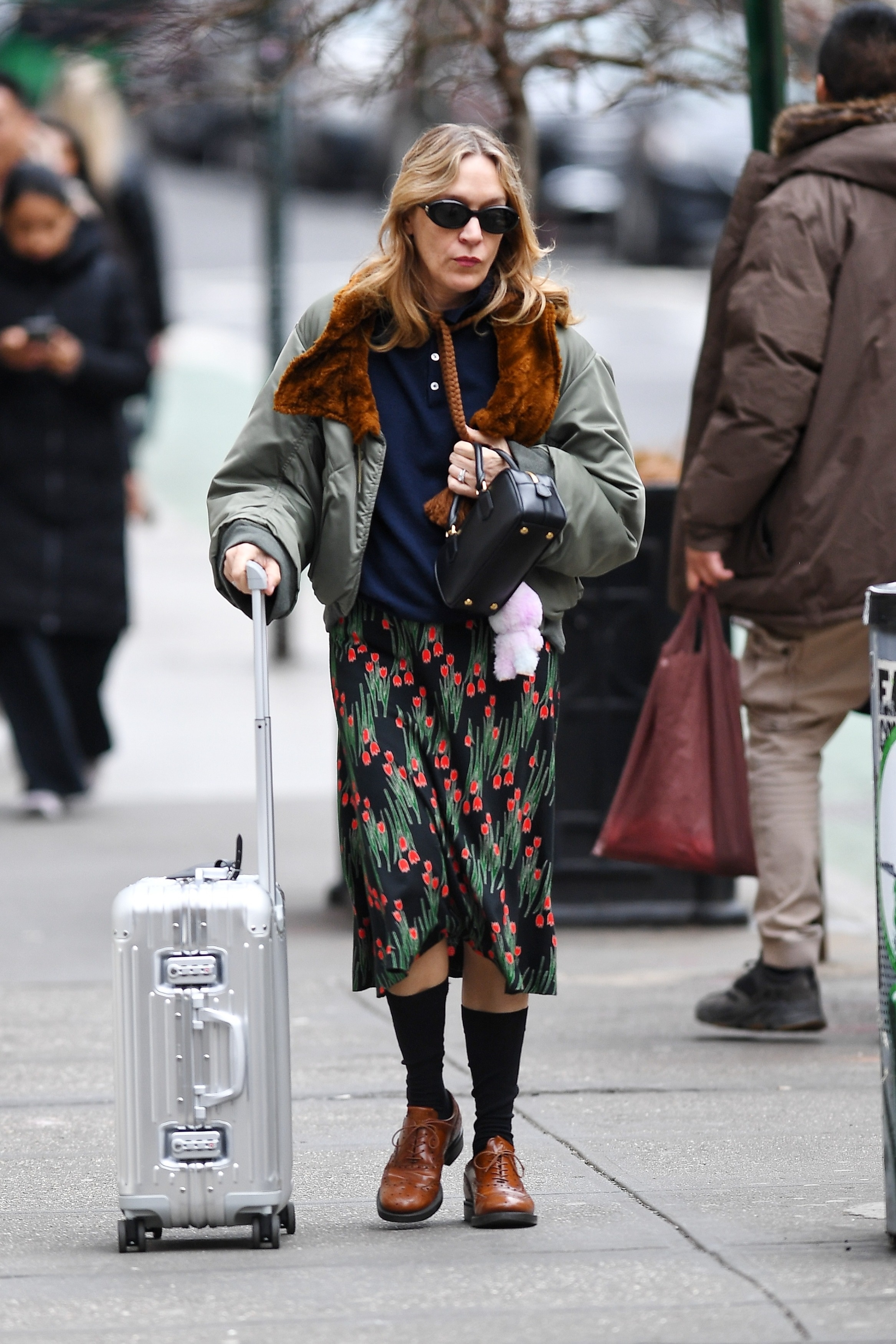 Chlo&amp;euml; Sevigny walking down the street with a suitcase.