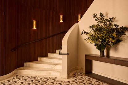 A stone curving staircase alongside wood-paneled walls