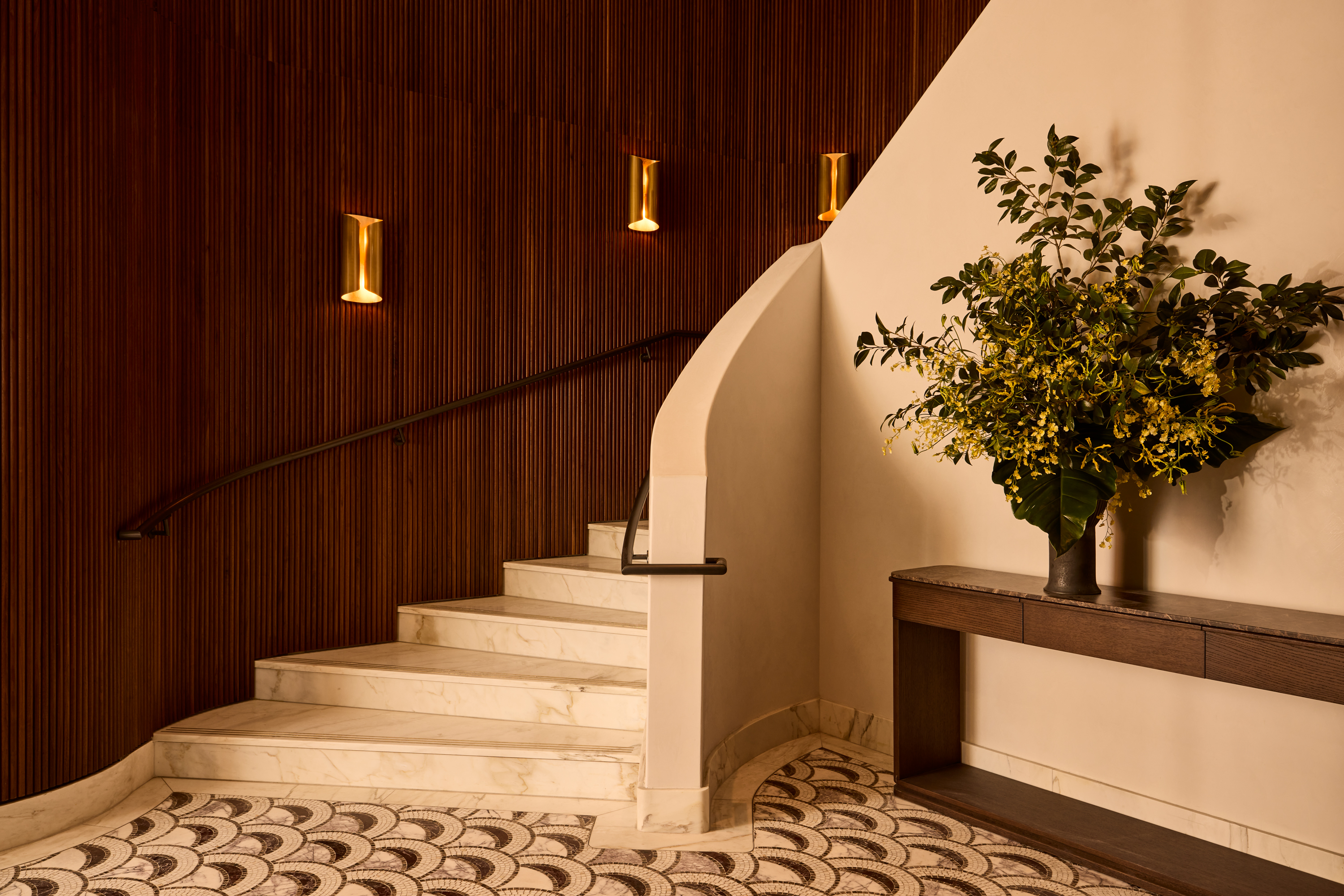 A stone curving staircase alongside wood-paneled walls